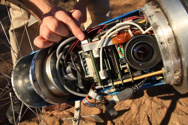 Close-up of an engineer's hand adjusting a camera system designed for a rover