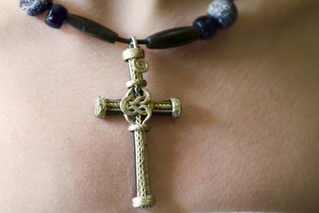 Close-up of a Christian cross worn as a pendant around a woman's neck.