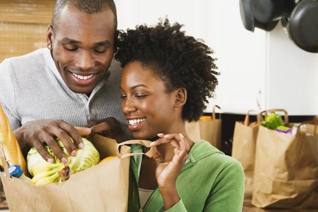 A couple is unloading healthy foods from grocery bags.
