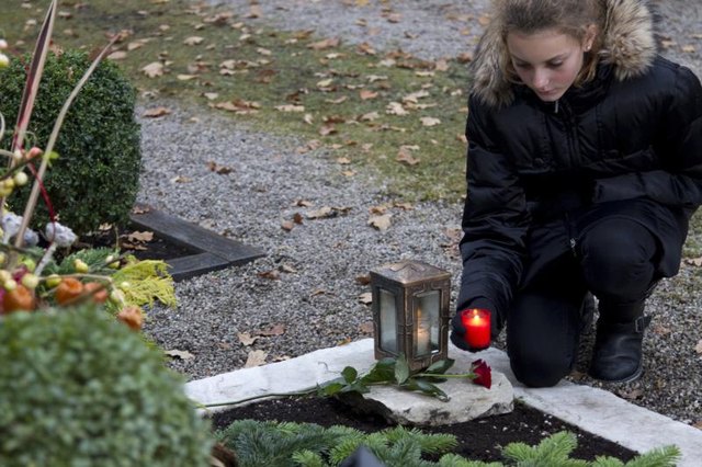 Teenager setting down red candles on sidewalk