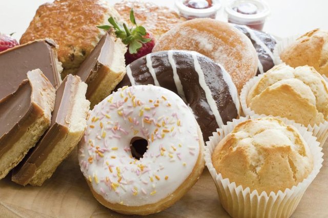 Assorted pastries including frosted doughnuts, peanut butter brownies, scones and jam.