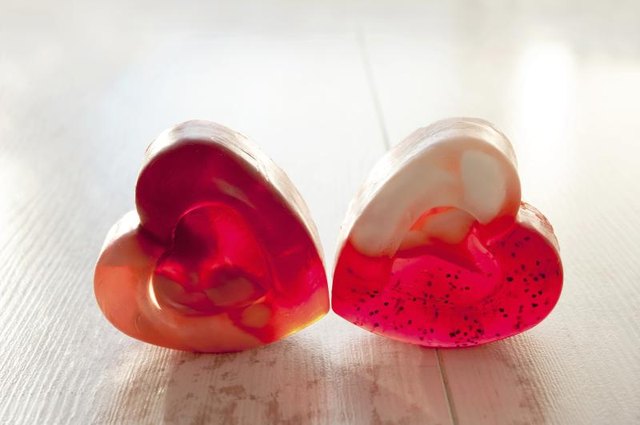 Two heart-shaped homemade soaps laying on a table.