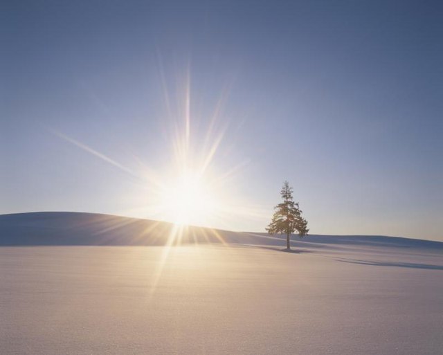 The sun rising over a snowy landscape.
