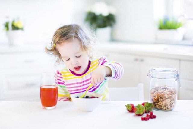 Toddler eating cereal with fruit