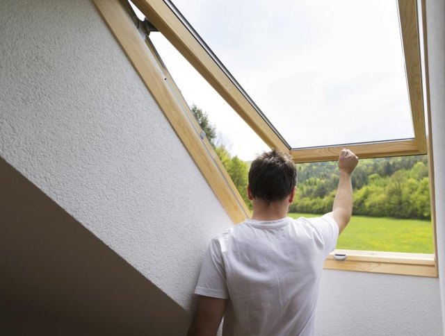 Man opening a skylight in the attic.