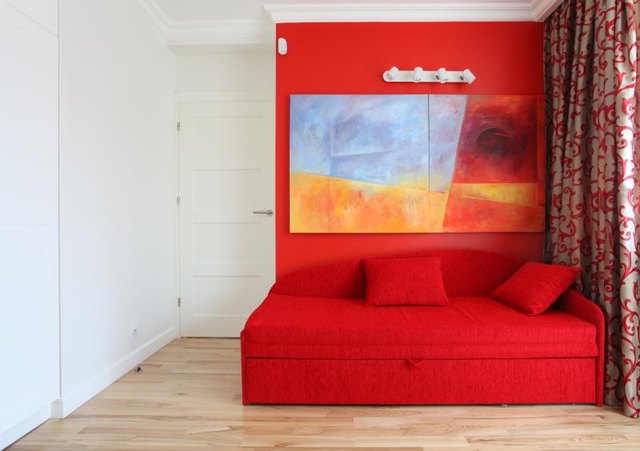 A small bedroom with contemporary art and sofa bed.