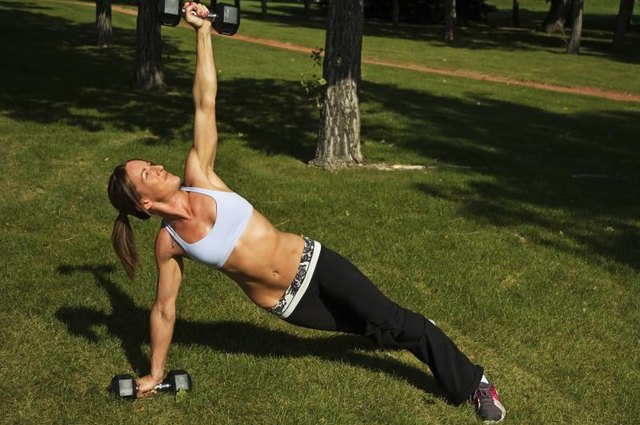 Woman doing side planks with weights in an outdoor park.