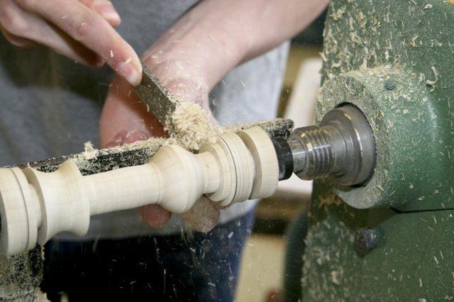 Hands working on a wood lathe.