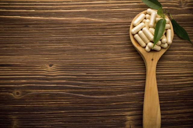 Vitamin supplements on wooden spoon.