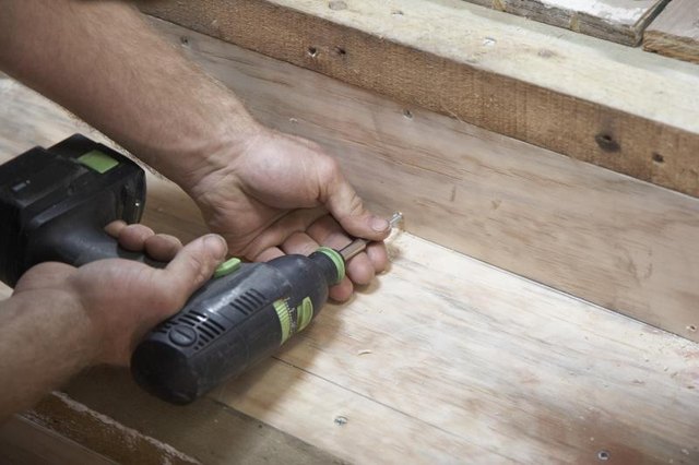 A carpenter is using a cordless drill to make a staircase.