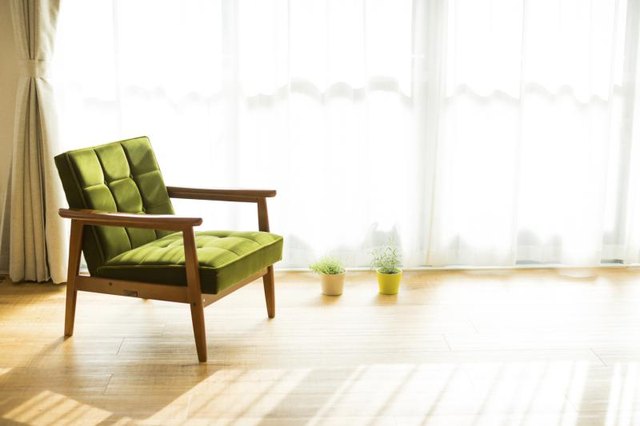 A mid-century modern chair in front of a sheer curtain.
