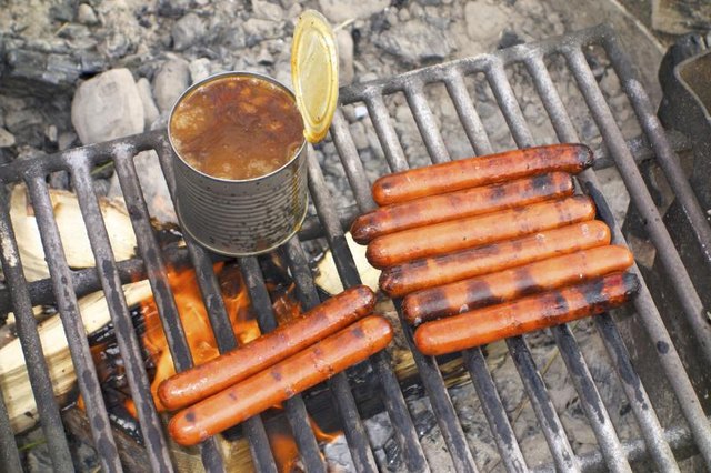 Hot dogs and a can of beans on campfire grill
