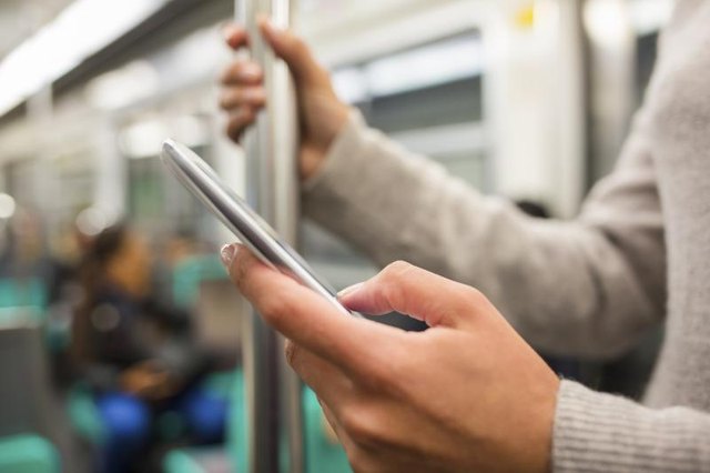 Woman's hands using a smartphone on the subway.