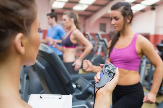 A fitness instructor uses a stopwatch while training a client with HIIT.