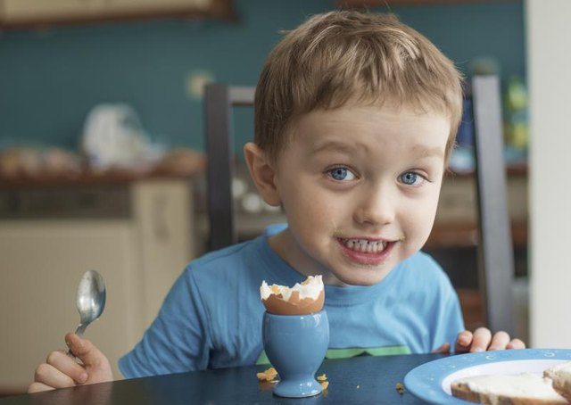 Smiling toddler eating an egg