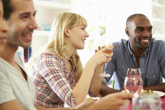 People laughing over pleasant conversation at a dinner party.