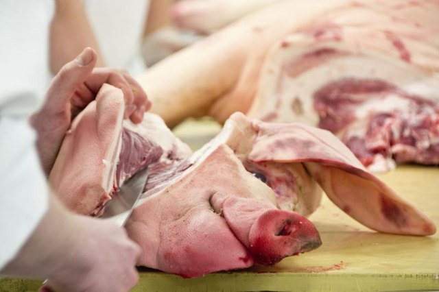 A butcher slicing pig cheeks.