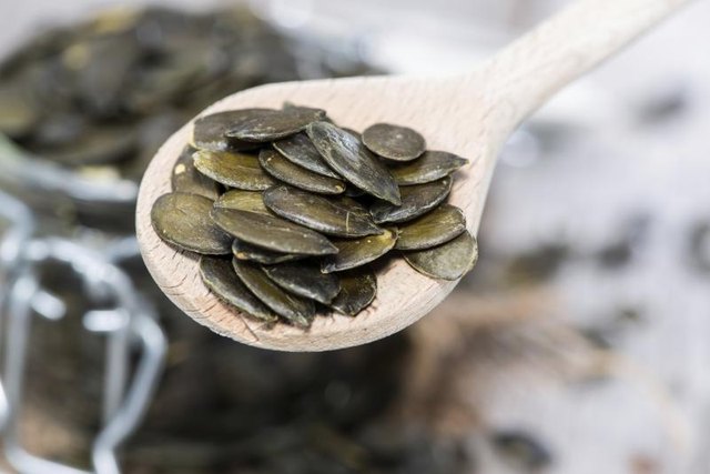 Pumpkin seeds on wooden spoon.
