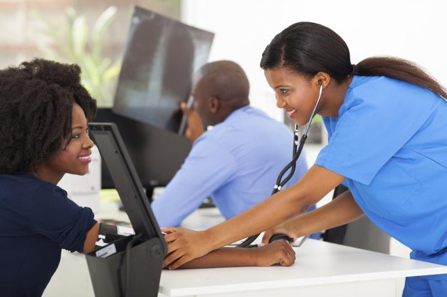 A medical assistant measures a patient's blood pressure in a doctor's office A medical assistant measures a patient's blood pressure in a doctor's office