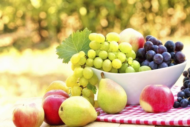 A bowl of red and green grapes on a table with fresh apples and pears A bowl of red and green grapes on a table with fresh apples and pears