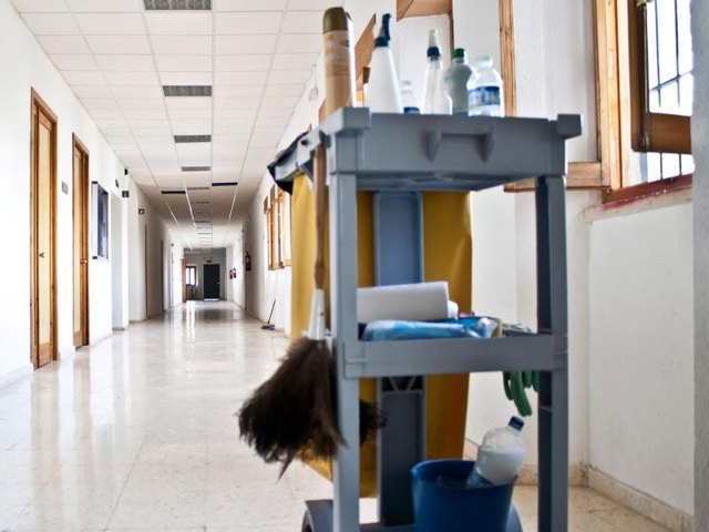 A cart with cleaning supplies in the corridor of a commercial building. A cart with cleaning supplies in the corridor of a commercial building.