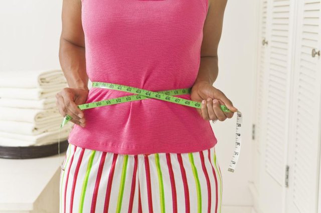 Woman using a tape measure on her waist. Woman using a tape measure on her waist.