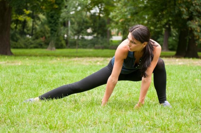 A woman in a lunge position outside in the park. A woman in a lunge position outside in the park.
