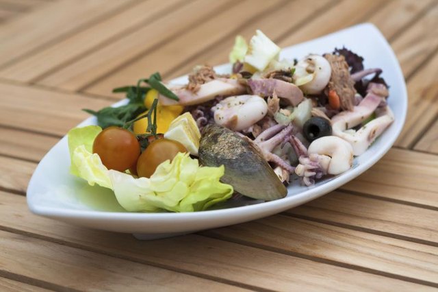 Mussels, squid and other seafood tossed on a platter with fresh vegetables, black olives and lemon. Mussels, squid and other seafood tossed on a platter with fresh vegetables, black olives and lemon.