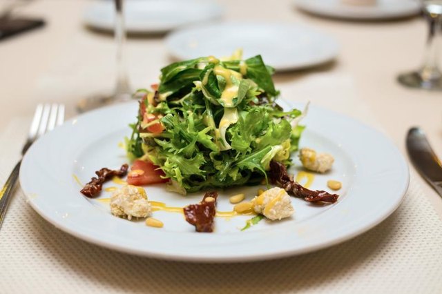A plate of spinach salad served with goat cheese and pine nuts. A plate of spinach salad served with goat cheese and pine nuts.