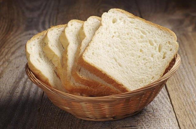 A basket filled with slices of white bread. A basket filled with slices of white bread.