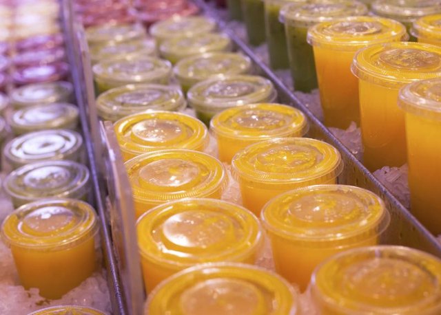 Fresh juices over ice in plastic cups with lids in a market. Fresh juices over ice in plastic cups with lids in a market.