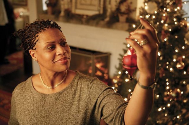 Woman hanging an ornament on a Christmas tree. Woman hanging an ornament on a Christmas tree.
