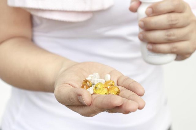 A woman is holding vitamins and supplements in her hand. A woman is holding vitamins and supplements in her hand.