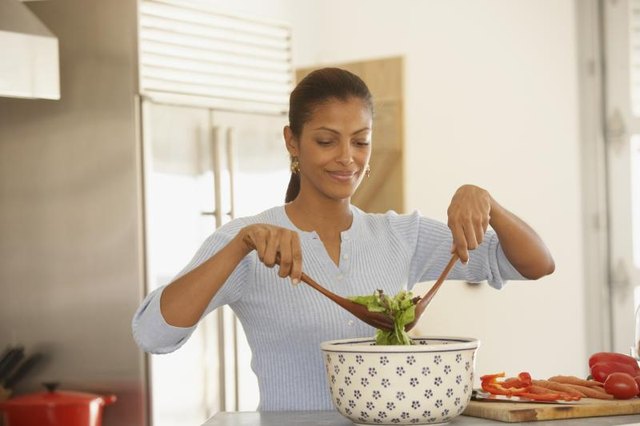A woman tossing salad in her kitchen. A woman tossing salad in her kitchen.