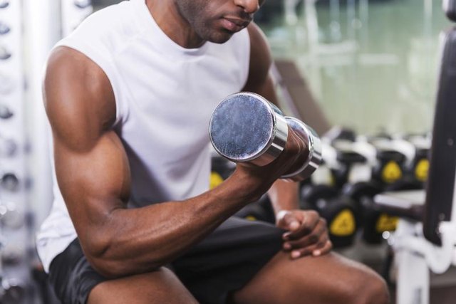 A man does bicep curls at a gym. A man does bicep curls at a gym.