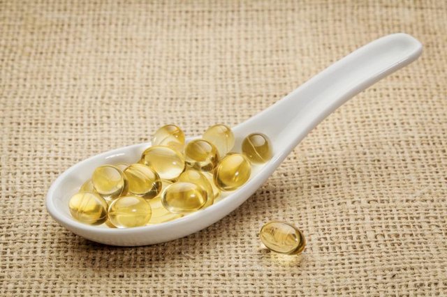 A ceramic spoon filled with fish oil capsules. A ceramic spoon filled with fish oil capsules.
