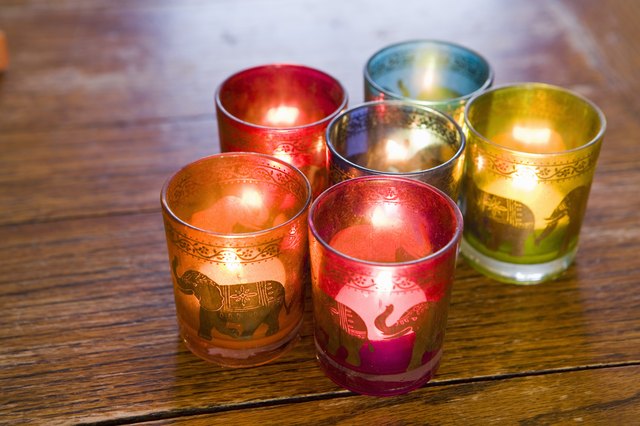 Candles in colorful glass holders on a table.