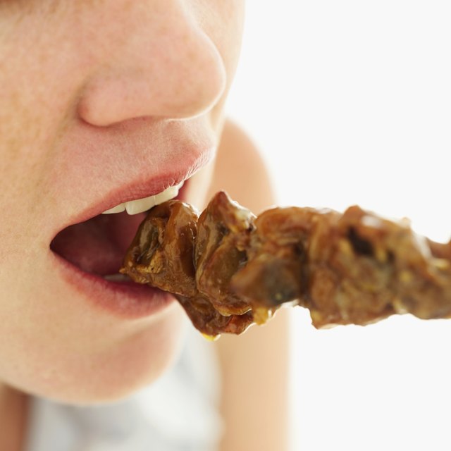 woman eating meat skewer