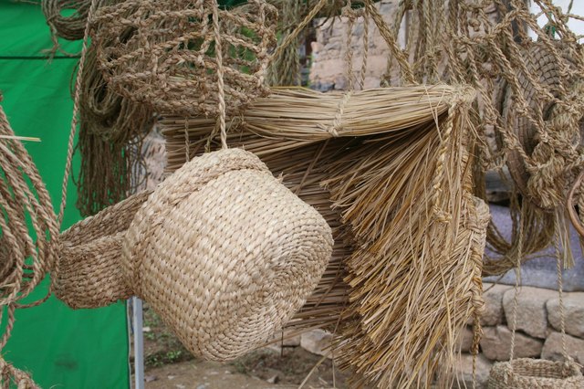 Straw baskets and brooms for sale at a craft fair.