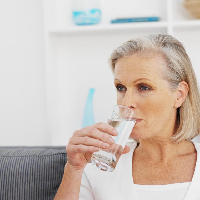 Older woman drinking glass of water.