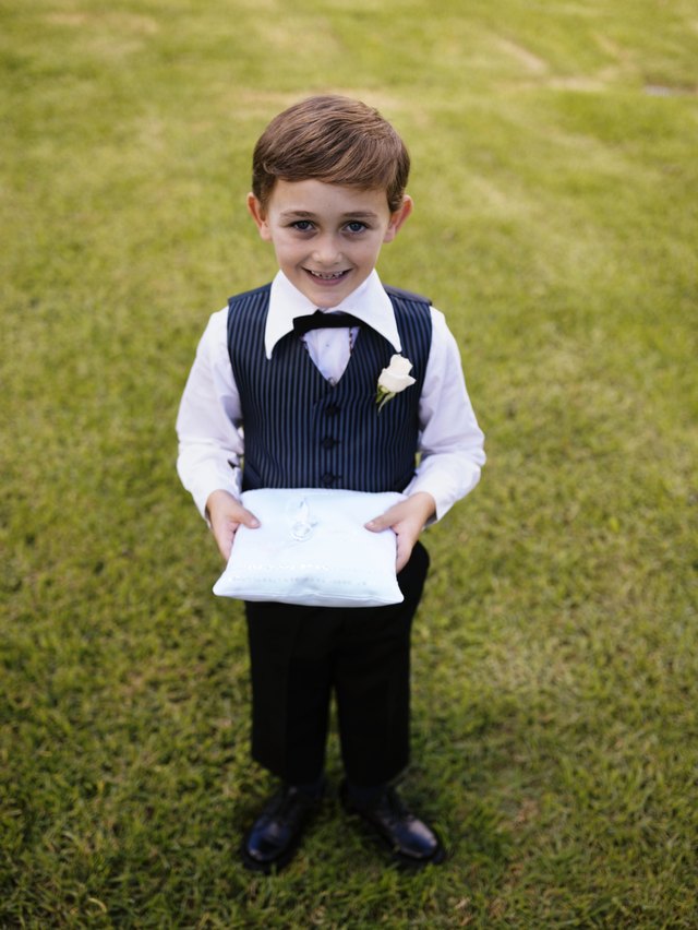 A ring bearer holds a satin pillow to present the wedding rings on.