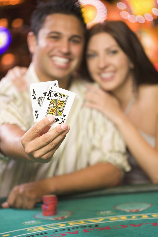 Couple holds up cards and blackjack table