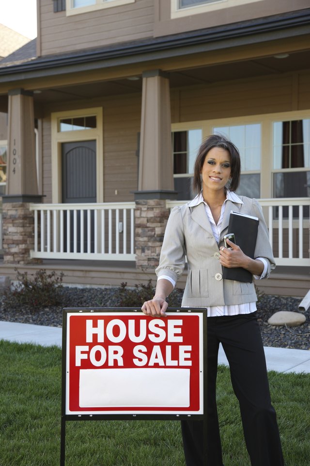A realtor stands in front of a home for sale.