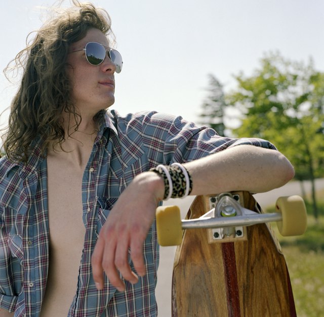 A skater rests his elbow on the top of a longboard.