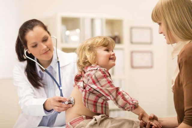 A pediatrician examining a child in an exam room with the mother.