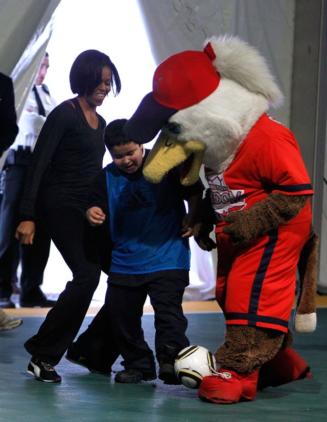 First Lady Michelle Obama, student and Eagle mascot kick soccer ball around