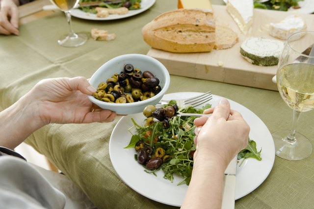 Woman adding olives to salad