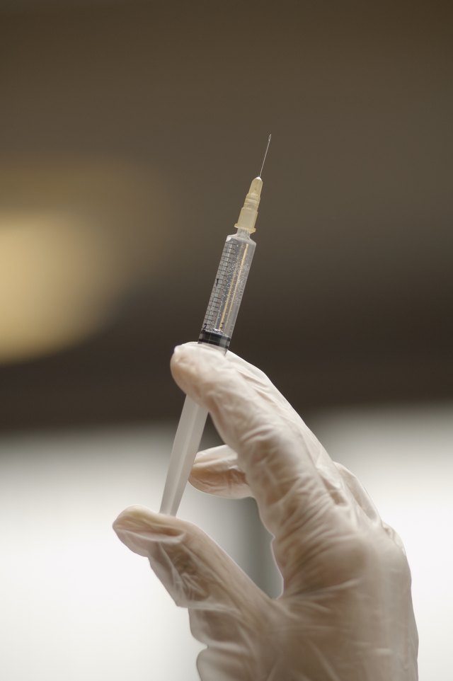 Gloved hand holding syringe