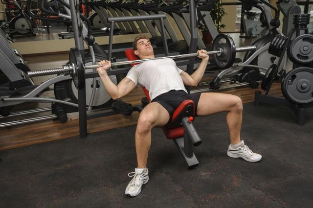 A man is exercising on an incline bench press. A man is exercising on an incline bench press.