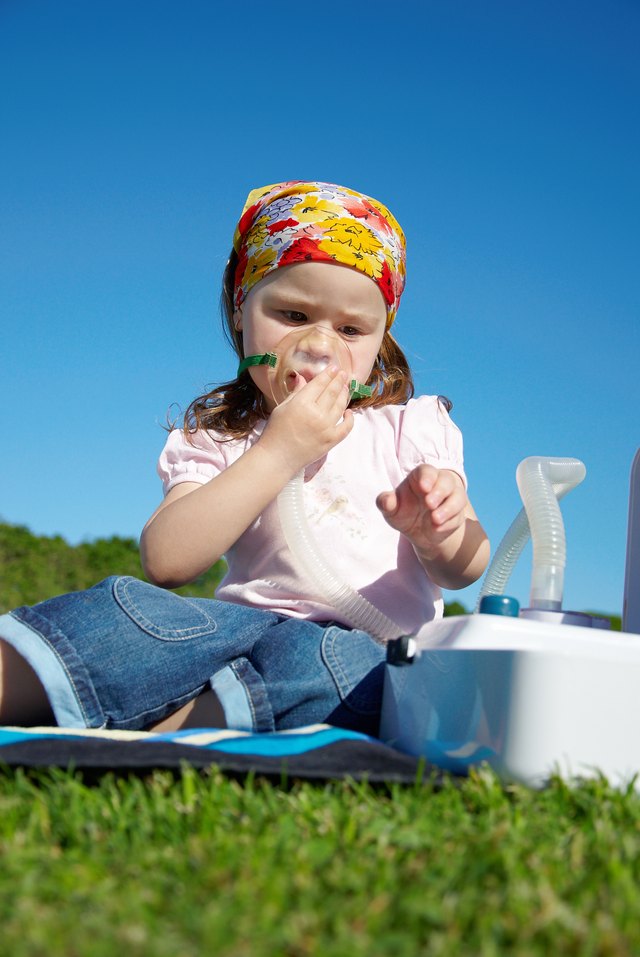 Young girl using nebulizer outdoors